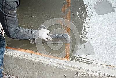 Contractor plastering wall with spatula, fiberglass mesh, plaster mesh after rigid insulation. Stock Photo