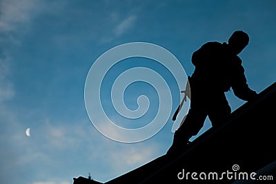 Contractor in Silhouette working on a Roof Top Stock Photo