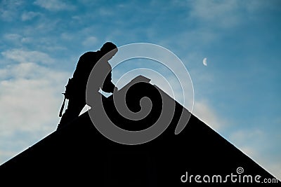 Contractor in Silhouette working on a Roof Top Stock Photo