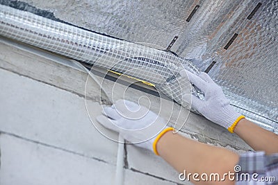 A contractor tapes a vapor barrier between a house and a cold attic Stock Photo