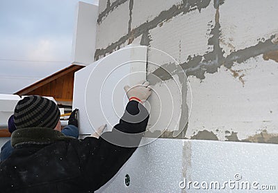 Contractors installing rigid styrofoam insulation board on house construction wall. House insulation outdoors Stock Photo