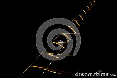 Contrast abstraction. Yellow lights and lines going diagonally upward on black background. Stock Photo
