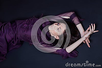 Contrast fashion Armenian woman portrait with big blue eyes lying on the floor in a purple dress. Lovely gorgeous girl posing Stock Photo