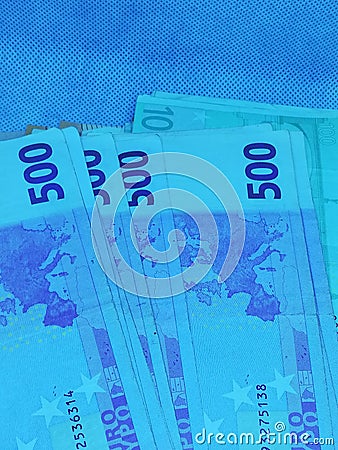 Control UV rays more banknotes of 500 and 100 euros on a bright blue background Stock Photo