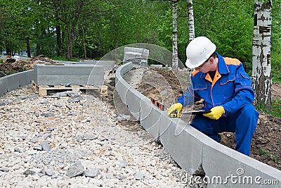 A control worker makes a measurement of the quality of the road construction course Stock Photo