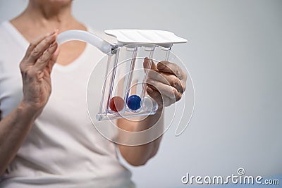 Convalescent woman inflates her lungs after surgery on special simulator Stock Photo