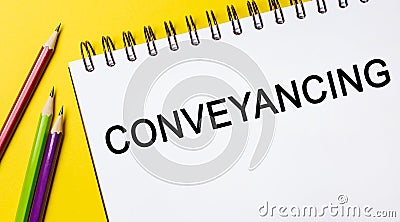 Conveyancing on a white notepad with pencils on a yellow background. Business concept Stock Photo