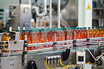 Conveyor line with plastic bottles of juice at modern factory equipment. Beverage manufacturing plant interior inside Stock Photo