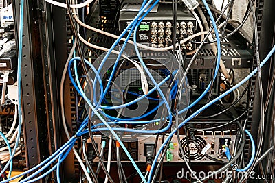 Convoluted mess of power sockets and tangled electrical cables tied together with zip ties hanging in a rack of electronic Stock Photo