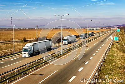 Convoy of White transportation trucks in line on a countryside highway Stock Photo