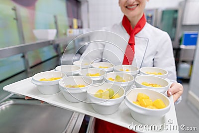 Cook in commercial kitchen showing tray with dessert Stock Photo