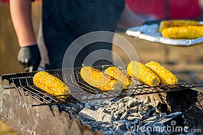 Cook in gloves fry corn on an open barbecue Stock Photo