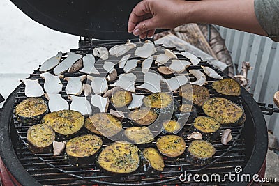 Cook hand pours spices on grilled vegetables Stock Photo