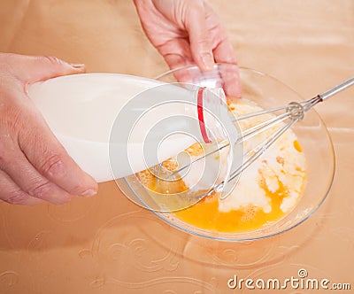Cook hands adds milk into dish Stock Photo