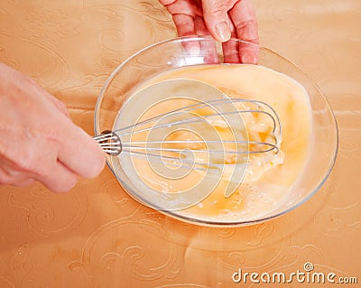 Cook hands beating up eggs and milk Stock Photo