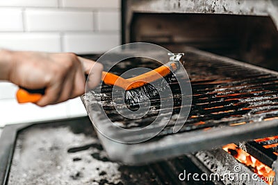 Cook hands with metal brush clean the grill oven Stock Photo