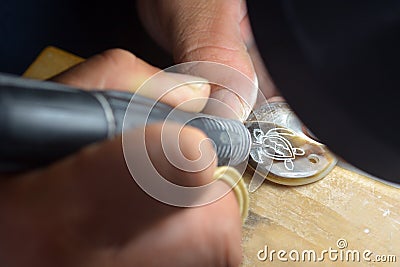 Cook Islander Maori engraves sea turtle on a Black Pearl shell R Stock Photo