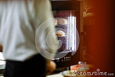 Cook look at the cooking sesame buns in the oven Stock Photo