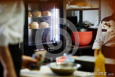 Cook look at the cooking sesame buns in the oven Stock Photo