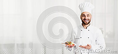 Cook Man Holding Plate With Chicken Presenting Dish In Kitchen Stock Photo