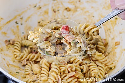 The cook mixes the pasta with a thick sauce and vegetables Stock Photo