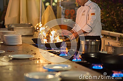 Cook prepares food on high heat. Hot dish Editorial Stock Photo