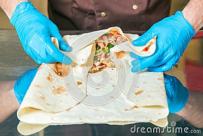 Cook prepares a shawarma. Ingredients in lavash. Stock Photo