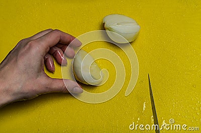 Cook slicing onions with a knife on a yellow cutting board Stock Photo