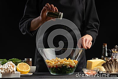 A cook sprinkles Italian seasoning in a salad,. Freeze in motion, Salad, organic ingredients and products. Vegetarian and tasty Stock Photo