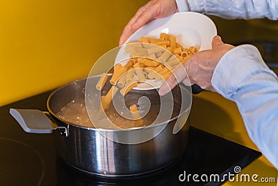 Cook throwing macaroni into a pot of boiling water Stock Photo