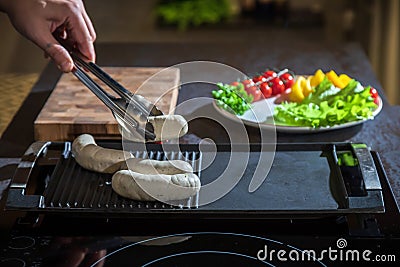 A cook turns over tongs of chicken to a grilled Stock Photo