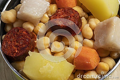 Cooked Cocido, Guiso stew, chickpeas with chorizo, bacon, carrot and potato in a green saucepan. Concept of traditional Spanish Stock Photo