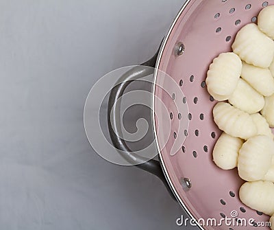 Cooked gnocchi pasta in pink colander Stock Photo