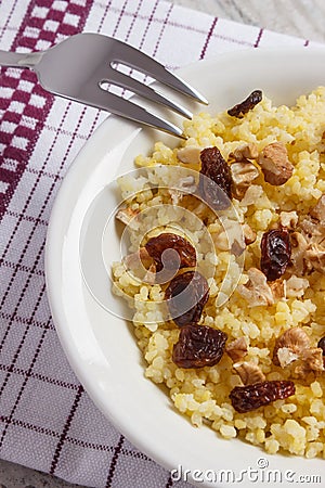 Cooked millet groats with walnuts on white plate, healthy food and nutrition Stock Photo
