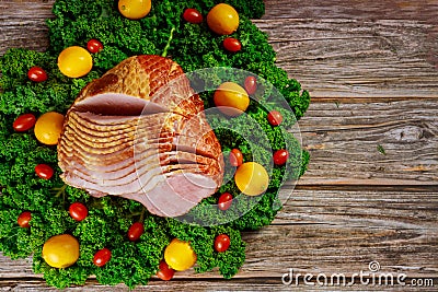Cooked spiral sliced hickory smoked ham with fresh lemon, kale and tomatoes Stock Photo
