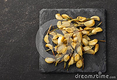 Cooked vegetables on black plate and dark background, baked garlic Stock Photo