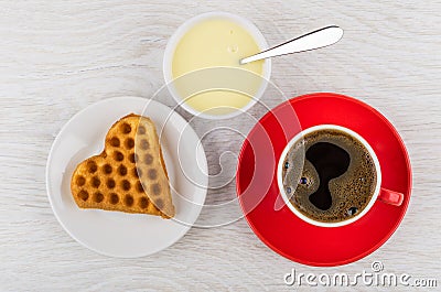 Cookie on saucer, coffee, condensed milk and spoon on table Stock Photo