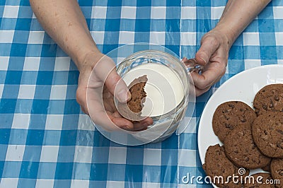 A person dunking a cookie in a glass of milk Stock Photo