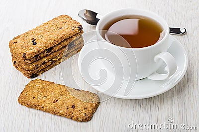Cookies-muesli, cup of tea on saucer, teaspoon on table Stock Photo