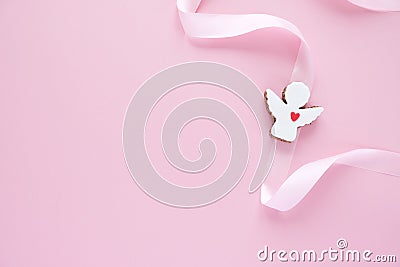 Cookies in the shape of an angel with pink ribbon on pink background. Stock Photo