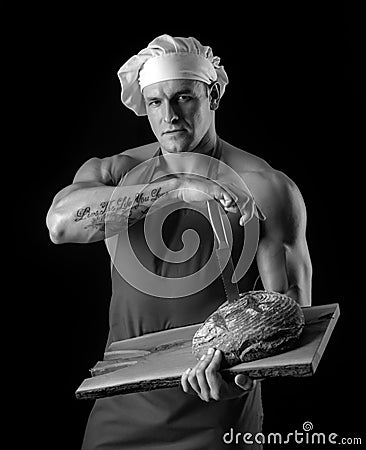 Cooking and baking. Chef baker man in apron. Sexy guy with bread and knife. Stock Photo