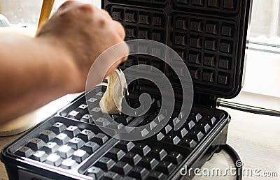 cooking Belgian waffles in a waffle iron. Pour in the dough. Stock Photo