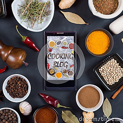 Cooking blog concept. Indian spices, herbs and smartphone on black Stock Photo