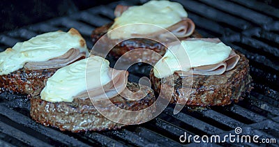 Cooking a burger patty with melted cheese and ham on a grill Stock Photo