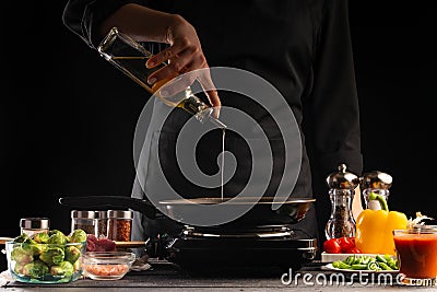 Cooking, the chef pours oil in a pan, against the background of vegetables. Cooking. Recipe book, cooking and gastronomy Stock Photo