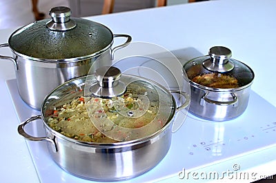 Cooking dinner on the electric stove in the modern kitchen. Chrome food pans Stock Photo