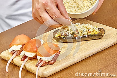 Cooking, food close up of male hands grating cheese sprinkled on the stuffed eggplant Stock Photo