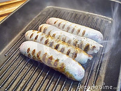 Cooking four sausages on a grill. Stock Photo