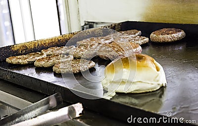 Cooking and Fraying Burgers and Hamburgers on Grill with Bread Loaf Stock Photo