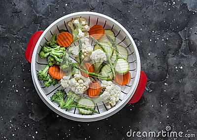 Cooking healthy food concept. Fresh vegetables broccoli, zucchini, carrots, asparagus in a steamer on a dark background, top view Stock Photo